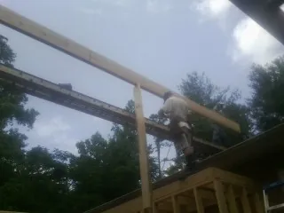 Carpenter setting a ridge beam over a new addition frame — Ice Dam Removal by Roofing Brothers in Coppell