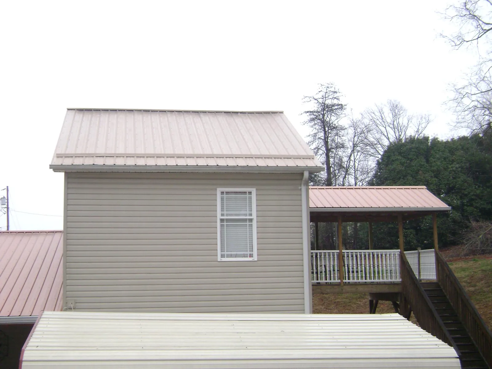 Tan metal roofs on a two story addition and attached porch, from a Roof Replacement job in Coppell