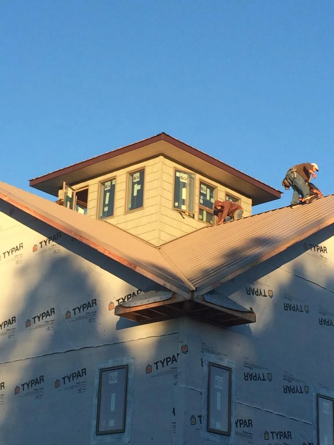 Roofers working around a rooftop cupola on a new metal roof at sunset — Roof Waterproofing in Coppell by Roofing Brothers